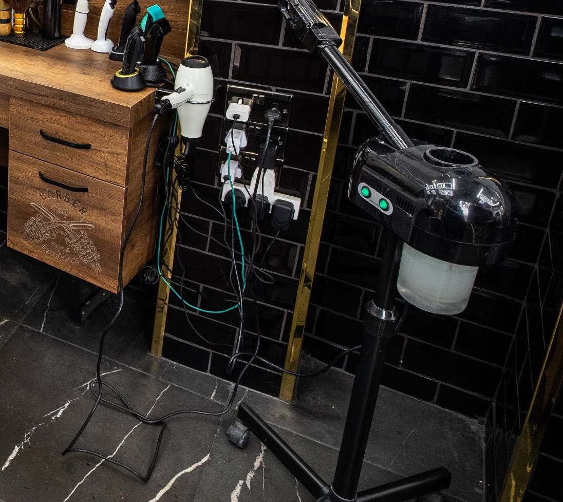 Clippers on their stands, a hair steamer and a wooden drawer carved with the word Barber